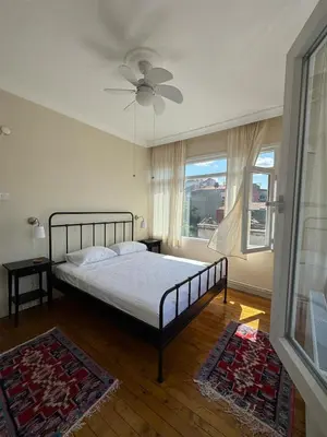 a bedroom with a bed with a ceiling fan and a window at The Kinyas House - Apartment in Kadıköy Historical Fishermen's Market in Istanbul
