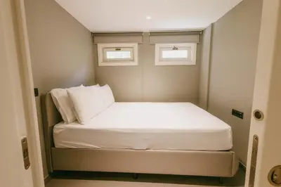 a small bed in a small room with two windows at Eva Bosphora Waterfront Living in Istanbul