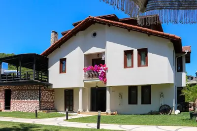 a white house with pink flowers on the balcony at Mints Hotel Ağva in Agva