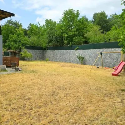a yard with a stone wall and a playground at Uludag Nefes Echoes by the Woods in Uludag