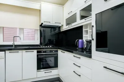 a kitchen with white cabinets and black counter tops at Stylish Flat w Balcony – 5 Mins from Taksim Square in Istanbul