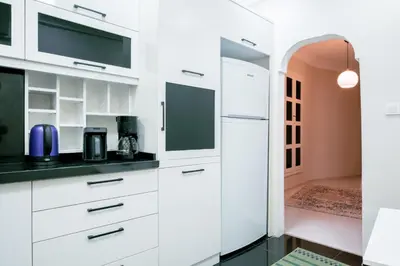 a kitchen with white cabinets and a doorway at Stylish Flat w Balcony – 5 Mins from Taksim Square in Istanbul