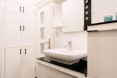 a bathroom with a white sink and white cabinets at Stylish Flat w Balcony – 5 Mins from Taksim Square in Istanbul