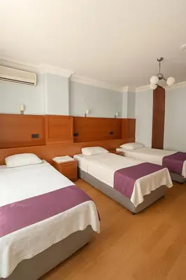 two beds in a room with wooden floors at Ferah Otel in Gebze