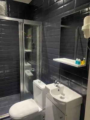 a black tiled bathroom with a toilet and a sink at Oldmile Palace Hotel in Istanbul
