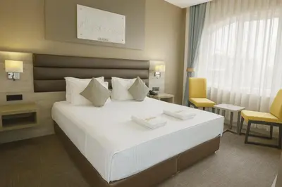 a bedroom with a large white bed and a yellow chair at Empire Hotel İstanbul in Istanbul