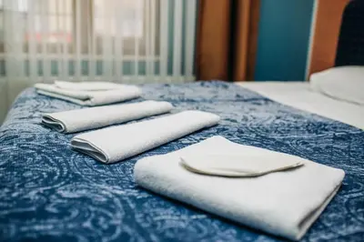 three white towels sitting on top of a blue bed at Ekinoks Hotel in İznik