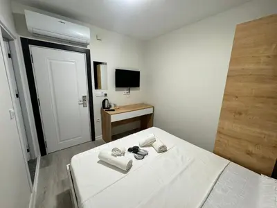 a white bedroom with a bed and a television at QLİNE HOTEL AİRPORT SaW in Istanbul