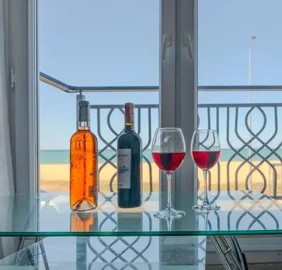 three wine bottles and glasses on a glass table on a balcony at İstanbul Airport Holiday Beach Hotel in Arnavutköy