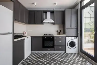 a kitchen with black cabinets and a washer and dryer at Amazing Luxury Duplex High Ceiling Patio! #403 in Istanbul