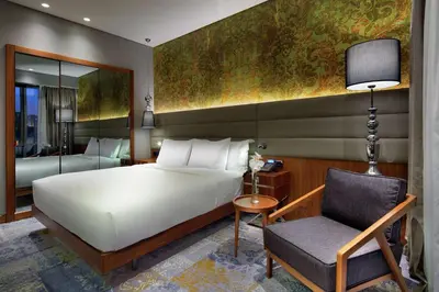 a bedroom with a large white bed and a chair at DoubleTree by Hilton Istanbul - Piyalepasa in Istanbul
