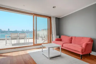 a living room with a red couch and a large window at Duplex Flat w Panoramic Bosphorus View and Terrace in Istanbul