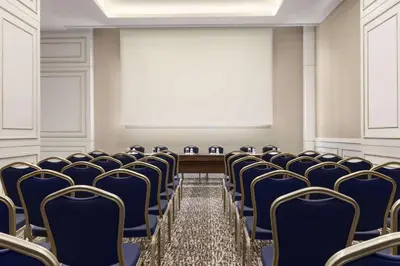 an empty conference room with blue chairs and a screen at Ramada by Wyndham Istanbul Merter in Istanbul