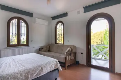 a bedroom with a bed and a couch and windows at 4BR all AC Pool BBQ Garden on Bagdat Ave Kirkpinar in Sapanca