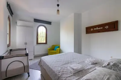 a bedroom with a bed and a chair and a window at 4BR all AC Pool BBQ Garden on Bagdat Ave Kirkpinar in Sapanca