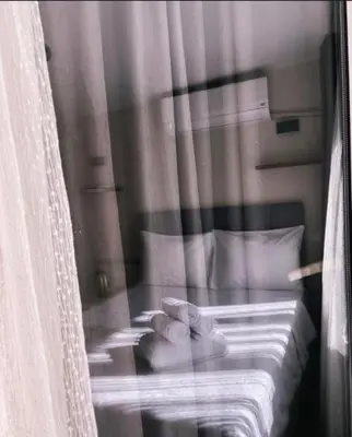 a window view of a bed with white sheets and pillows at Büyükada Çarşı Pansiyon in Adalar