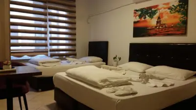 a room with three beds and a desk and a window at Hotel Kiwi in Istanbul