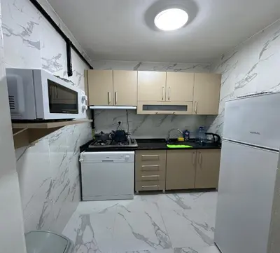 a small kitchen with white appliances and marble walls at Armagan Home Taksim in Istanbul