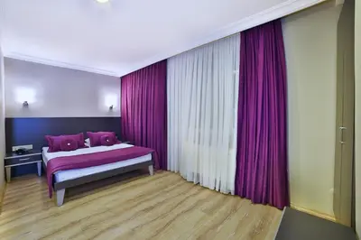 a bedroom with purple curtains and a bed with pink pillows at The Hera Premium Hotels in Istanbul