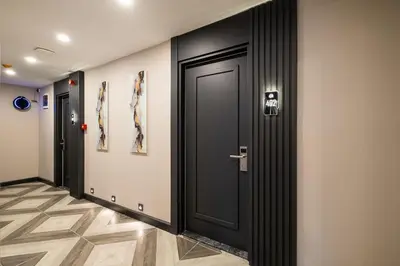 a hallway with a black door and paintings on the wall at 216 Star in Samandra