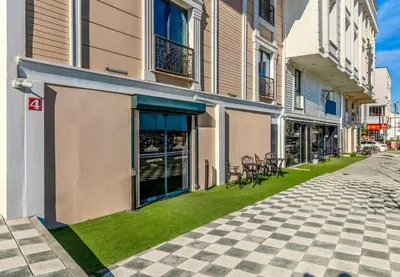 a building with chairs on the grass next to a sidewalk at AirGate Airport Hotel in Arnavutköy
