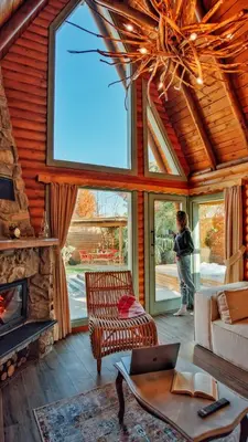a woman standing in a living room with a fireplace at Rast Sapanca Bungalov in Sakarya