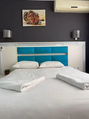 a bed with a blue headboard and two towels on it at Holiday Suit in Istanbul