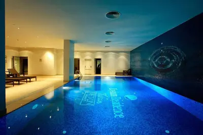 a large swimming pool with blue lighting in a building at Modern Comfort Steps from Taksim in Istanbul
