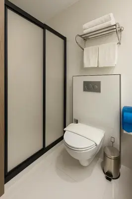 a white bathroom with a toilet and towels at Positive Hotel in Arnavutköy