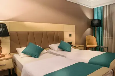two beds in a hotel room with green and white pillows at Hotel Bossuite Kadikoy in Istanbul