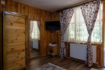a living room with wooden walls and windows and a television at Aytepepark Turistik tesisleri