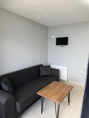 a living room with a black couch and a wooden table at Rumeli Pansiyon in Kumbağ