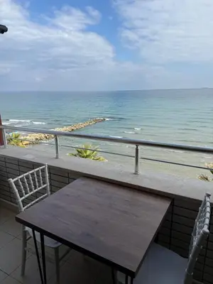 a table and chairs on a balcony overlooking the ocean at Rumeli Pansiyon in Kumbağ