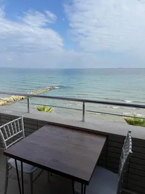a table and chairs on a balcony overlooking the ocean at Rumeli Pansiyon in Kumbağ