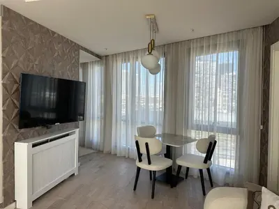 a living room with a table and chairs and a television at 91 sqm luxury apartment with double view in Istanbul