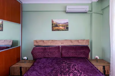 a bedroom with a wooden bed with purple sheets at Şehir Manzaralı Ferah Daire in Istanbul