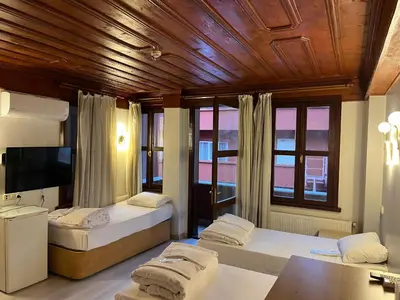 a room with two beds and a tv and windows at Adil Konak Hotel in Istanbul