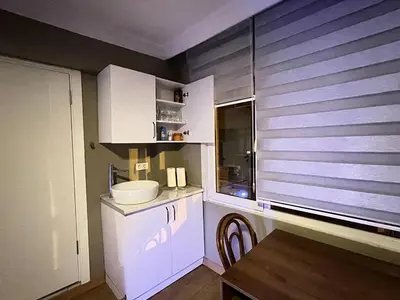 a kitchen with white cabinets and a wooden table at Konakkoy 1 in Istanbul