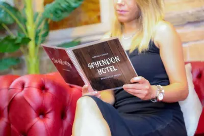 a woman sitting on a couch reading a book at Hotel SPHENDON in Istanbul