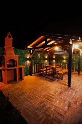 a wooden deck with a grill and tables at night at Zeyno Sapanca in Sapanca
