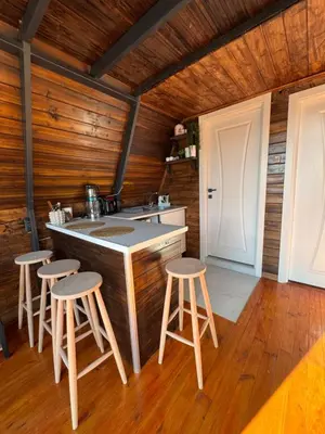 a kitchen with wooden walls and a counter with stools at Shadeoffgreenbungalow