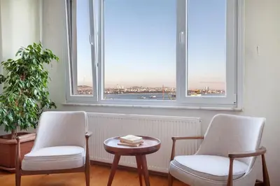 two chairs and a table in a room with two windows at Historic Elegance with a Bosphorus Gaze in Istanbul