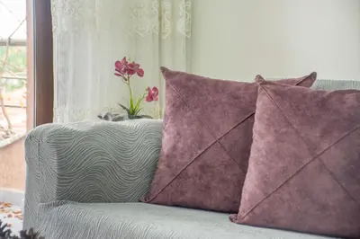 a couch with two pillows and a vase with flowers on it at Cozy 1BR & Sofabed with Two Inviting Balconies in Beylikduzu