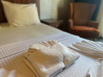a bed with white towels on it with a chair at Ser Suite Apart Hotel in Esenyurt