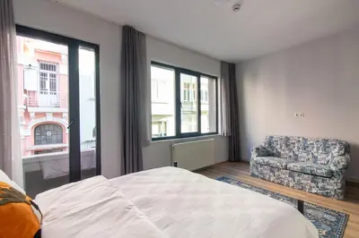 a bedroom with a bed and a chair and windows at Modern and Cozy 2BR in Vibrant Cihangir in Istanbul