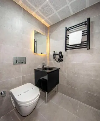 a bathroom with a toilet and a sink and a mirror at Cosinüs Airport Hotel in Arnavutköy