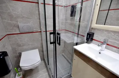 a bathroom with a shower and a toilet and a sink at Tüm Palace Otel in Bandırma