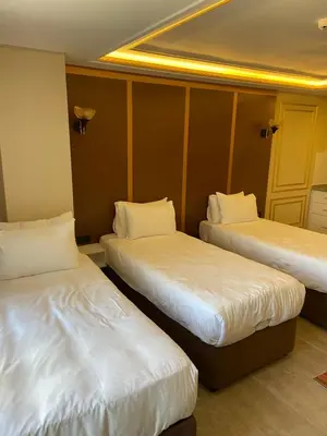 a room with three beds with white sheets at Istanbul Town Hotel in Istanbul