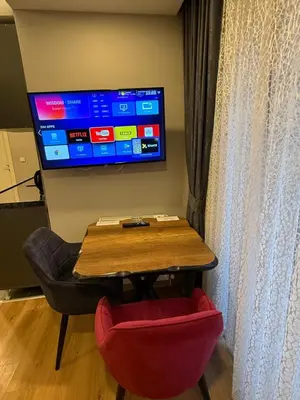 a table with a red chair and a television on a wall at AYD Apartment Taksim in Istanbul
