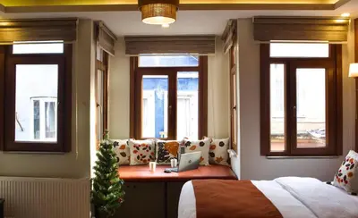 a bedroom with a bed and windows with a laptop on a desk at PeraHomes DE in Istanbul